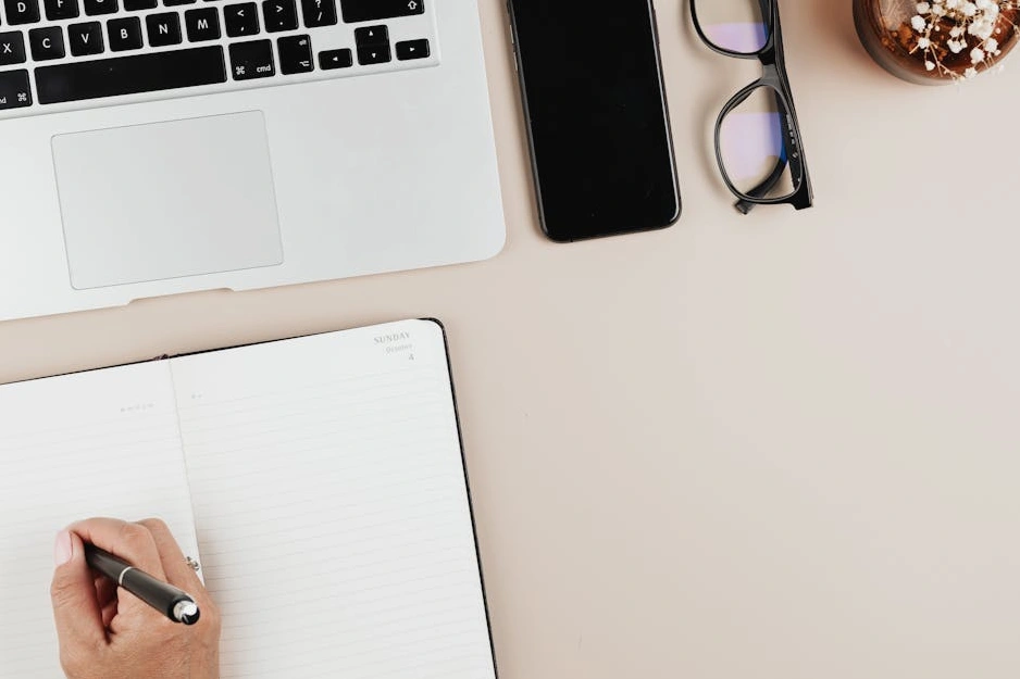 Masanın üzerinde duran bir deftere notlar alan bir kişi